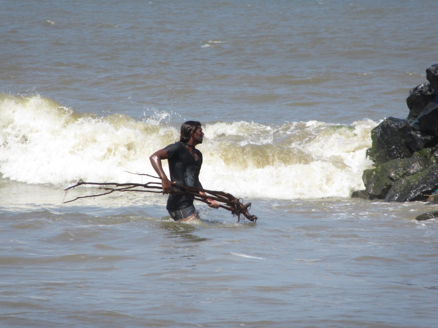 Surflehrer Vicky räumt Unrat aus dem Surfbereich weg.