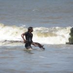 Surflehrer Vicky räumt Unrat aus dem Surfbereich weg.
